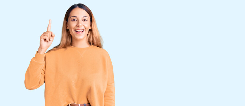 Beautiful young woman wearing casual clothes pointing finger up with successful idea. exited and happy. number one.