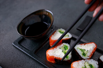 Eating sushi. Chopsticks taking sushi from plate