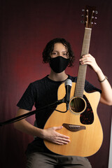 Musician plays acoustic guitar wearing a face mask due to 2020 pandemic and social distancing measures