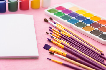 Fototapeta premium Watercolor paints and brushes for drawing on a pink background. Copy space.