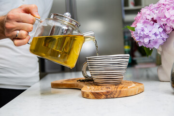 Making perfect loose tea. Pouring tea from a teapot into a porcelain cup.