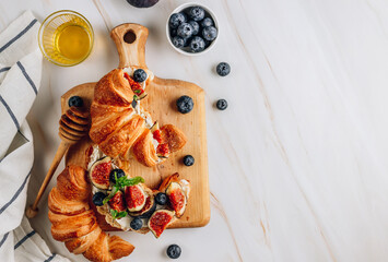 Delicious sweet sandwich with croissants, soft cheese, blueberries and figs