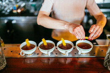 Cuatro tazas de te con cascaras de limón en una barra de un bar