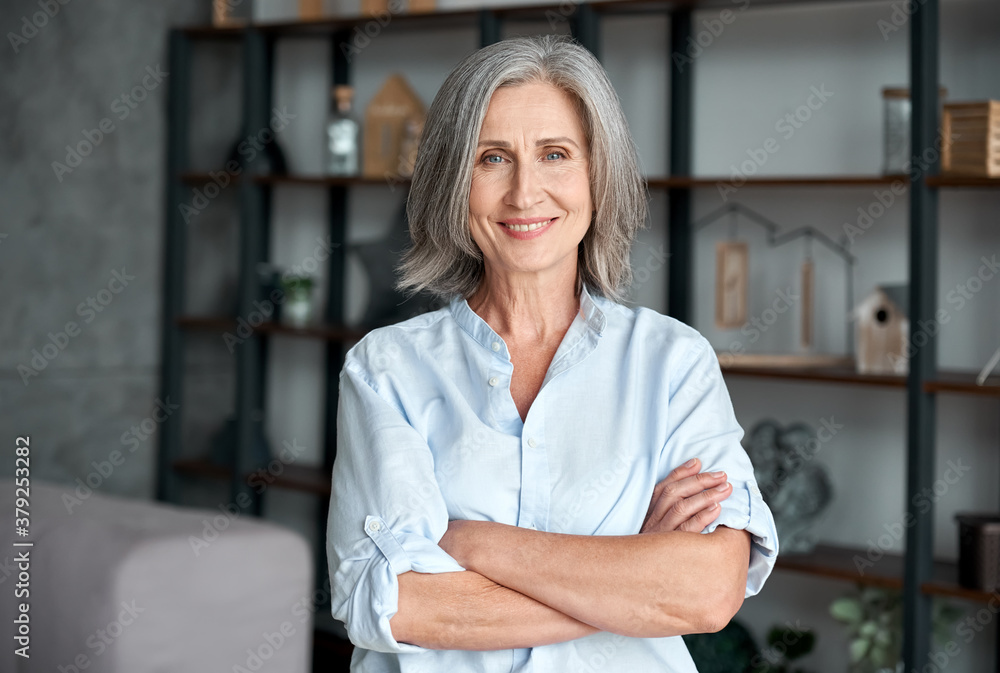 Wall mural smiling confident stylish mature middle aged woman standing at home office. old senior businesswoman