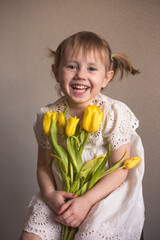 A Portrait of a beautiful little girl with a bouquet of yellow tulips flowers