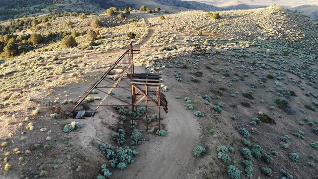 Drone flight semicircle radius around old wooden mining head frame in the desert.