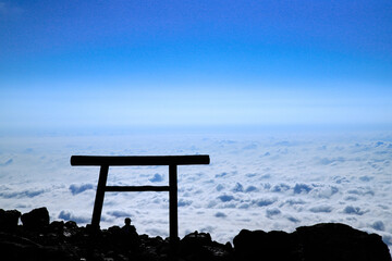 那須の茶臼岳を照らす太陽と、眼下に広がる雲海と鳥居
