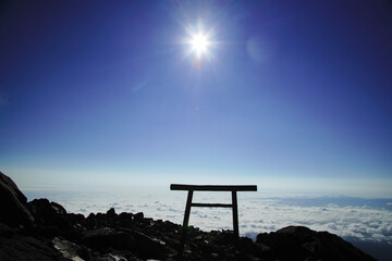 那須の茶臼岳を照らす太陽と、眼下に広がる雲海と鳥居
