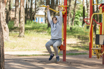 Single young man doing exercises on the sports ground in the park, street workout. Fitness outside. Exercising alone for Covid-19 prevention - Image