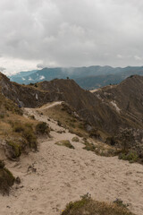 landscape between mountains with a sandy road and cloudy sky