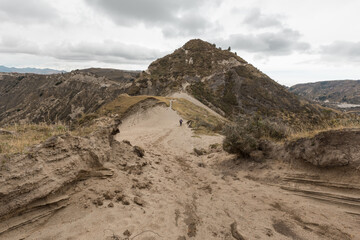 view of a road with sand in the Andean mountains, cloudy sky and local vegetation, angular