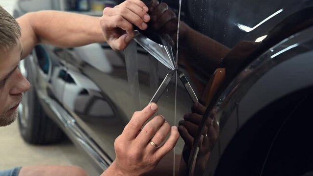 Cutting paint protection film with a special knife tool on a black car