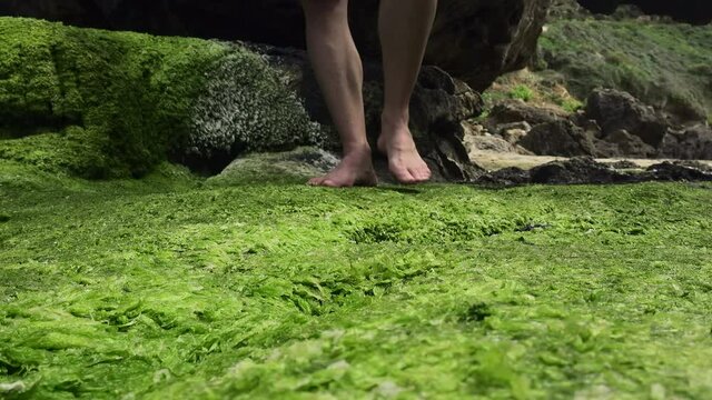Man walking barefoot stepping on moss