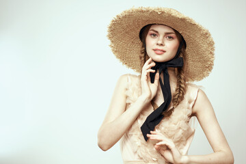 Nice girl in a straw hat with a black ribbon and in a dress on a light background romance model fun emotion