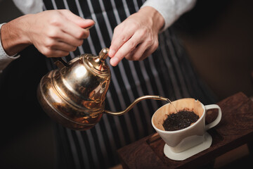 Hand drip coffee filter, barista pouring hot water on roasted coffee ground with filter