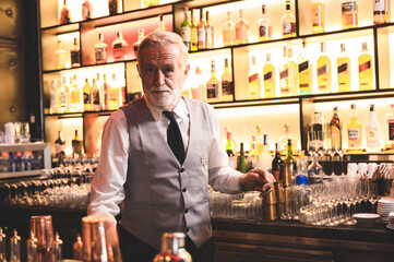 Expert barman is making cocktail at night club, senior bartender working at bar counter