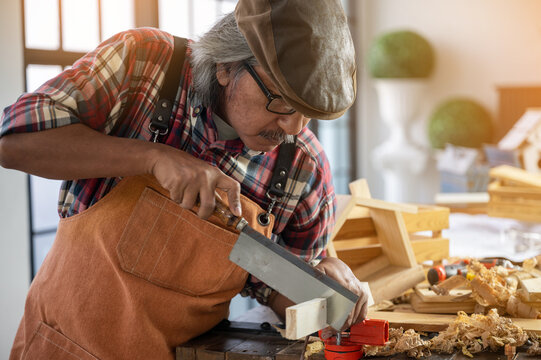 Carpenter working on wood craft using saw and ruler tools for hand crafting at workshop to produce construction material or wooden furniture . DIY maker and carpentry work concept.