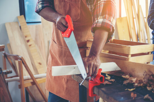 Carpenter working on wood craft using saw and ruler tools for hand crafting at workshop to produce construction material or wooden furniture . DIY maker and carpentry work concept.