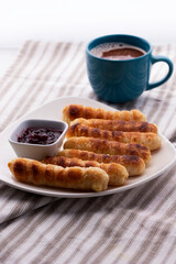 Merienda colombiana. pasteles horneados rellenos de queso con pasta crujiente. Comida para la tarde llamada deditos de queso con bebida de chocolate caliente.