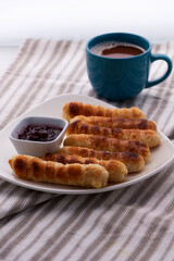 Merienda colombiana. pasteles horneados rellenos de queso con pasta crujiente. Comida para la tarde llamada deditos de queso con bebida de chocolate caliente.