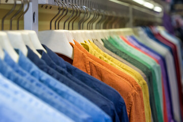 Bright colorful cotton shirts on hanger in boutique shop close up