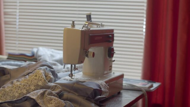 Slow dolly in of sewing machine on table with cloth