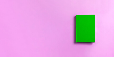 green book on pink background.   ピンク背景の上の緑色の本