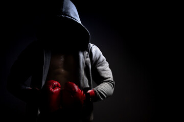 man with red boxing gloves and hood on a dark background