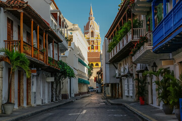 Fototapeta na wymiar View to the clock tower of Cartagena cathedral with blue sky through a narrow street in shadow, Cartagena, Colombia, Unesco World Heritage 