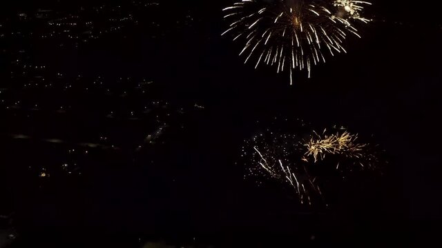 Aerial shot of fireworks with city lights in the background.  City Night Lights.  4K footage.