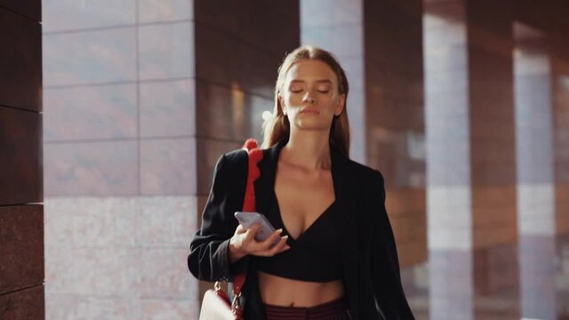 Serious young attractive woman hurry up walking look around use phone business lady beauty pretty internet technology urban message fashion slow motion
