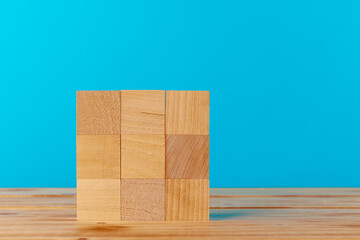 Stacked wooden blocks on wooden desk against blue background