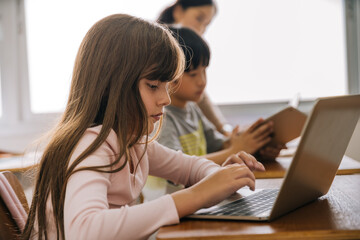 School children using computer laptop in school classroom, digital native, technology, learning. Diversity group of students in computer class.