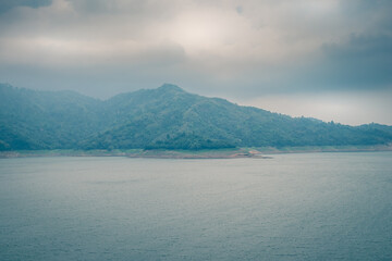 Scenic mountain range next to deep river shrouded in mist landscape view at Thailand.