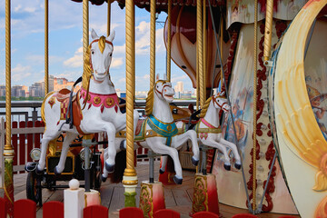 Old carousel in a holiday park. Horses and airplane on a traditional fairground vintage carousel. Merry-go-round with horses.