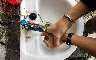 Young man washing hands with soap over sink