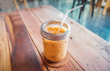 Iced coffee in cup on a wooden table at the cafe. Cold espresso in the coffee shop. Beverage glass...