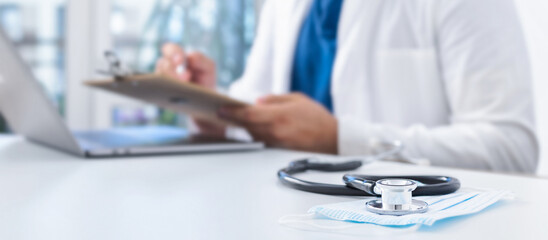 Online medicine concept. Stethoscope and medical mask on the doctors desk in the background, the...