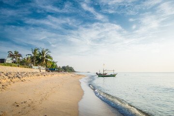 Obraz premium Beautiful view of the turquoise waves with the blue sky and white clouds and fisherman's boat on sandy beach on vacation in Hua Hin, Prachuap Khiri Khan Province, Thailand.