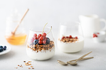 Breakfast, granola with yogurt and berries in a jar on a light background