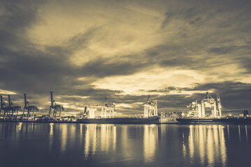 Harbor with anchored ship. Container cargo freight ship with working crane bridge at a shipyard in for logistic transportation import and export at Asia haven port background, Samutprakarn, Thailand.