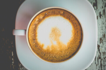 Hot latte art on wooden table at coffee shop. White cup of coffee the best start to any morning at cafe with copy space. Top view