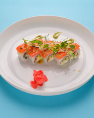 White rice sushi set with salmon fish and chia seeds served on a big white plate with ginger and wasabi sauce.