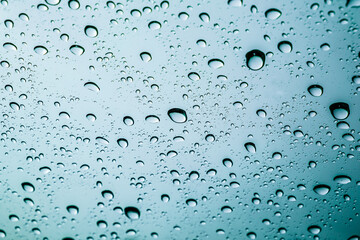 Colourful drops of rain on a window glass in the city. Image of raindrops texture background.