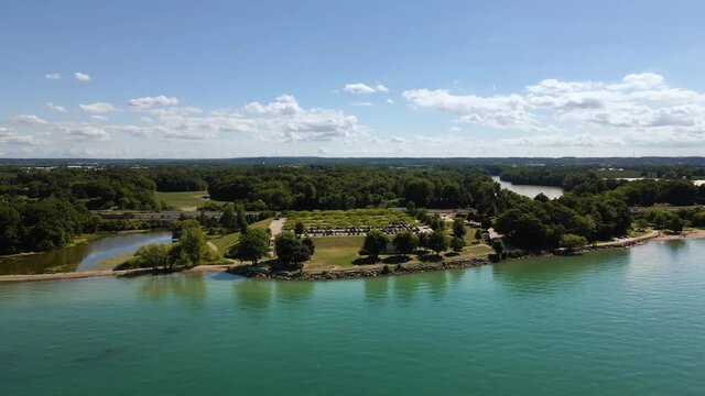 Aerial view of a beautiful green park next to an emerald Lake Ontario. Cars driving on the highway through Charles Daley Park on the shore of Lake Ontario in Canada.