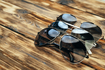 Set of dark sunglasses on brown wooden surface
