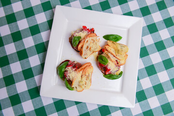 Traditional Italian appetizer Bruschetta with roasted tomatoes, mozzarella cheese, strawberry, garlic and herbs.