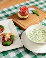 ummer cold soup Okroshka, vegetable and fruit salad and Italian strawberry dessert on a table.