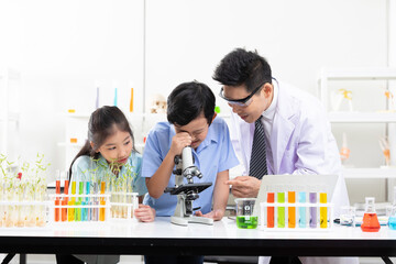 asian science teacher teaching how to using microscope with child students in laboratory classroom