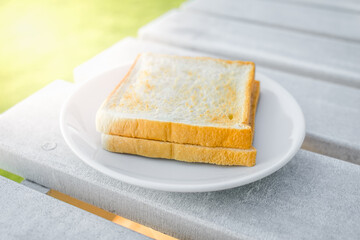 Toast bread in white plate on wooden table.